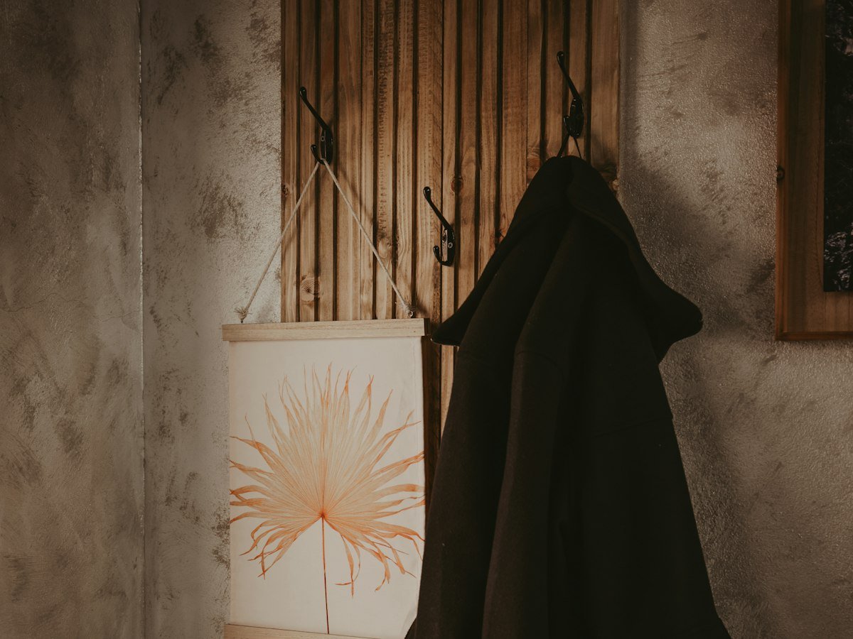 Manteau noir accroché à un porte-manteau mural en bois