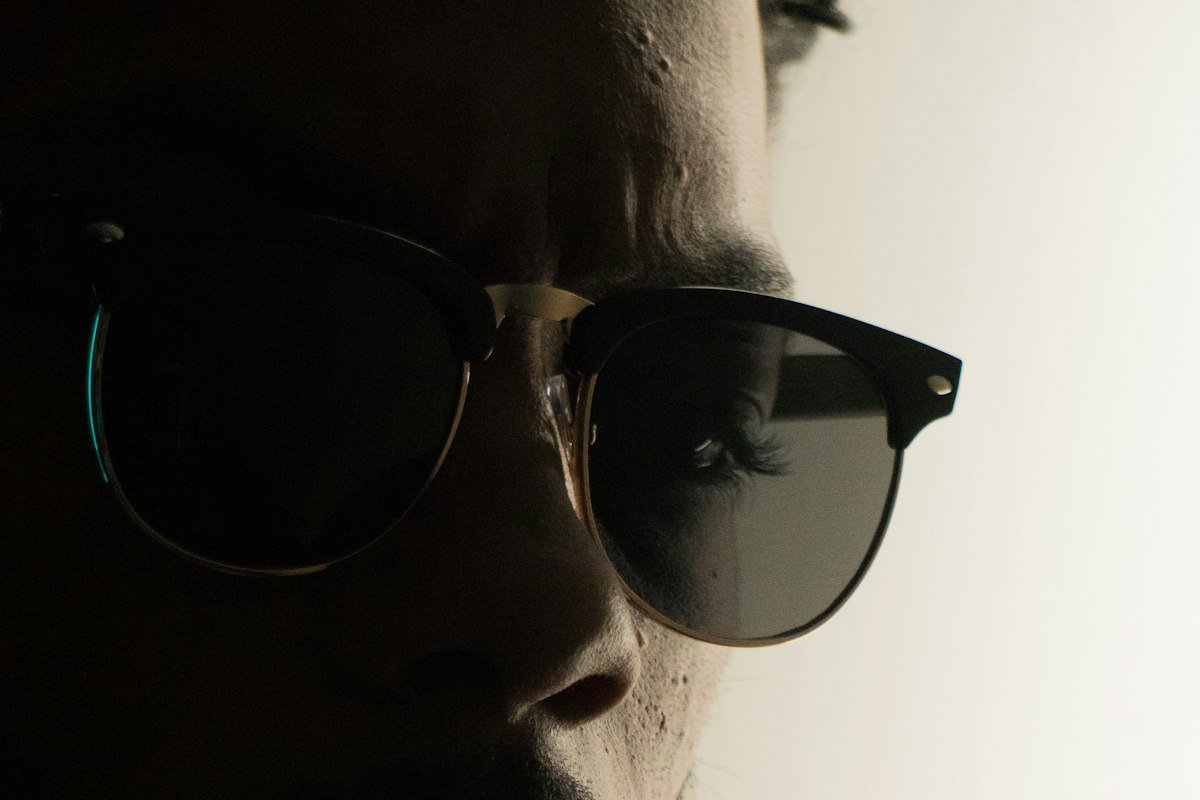 Homme portant des lunettes noires dans une lumière chaude